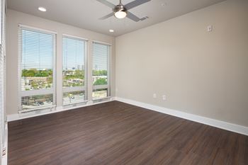 A bedroom with a ceiling fan and floor to ceiling windows